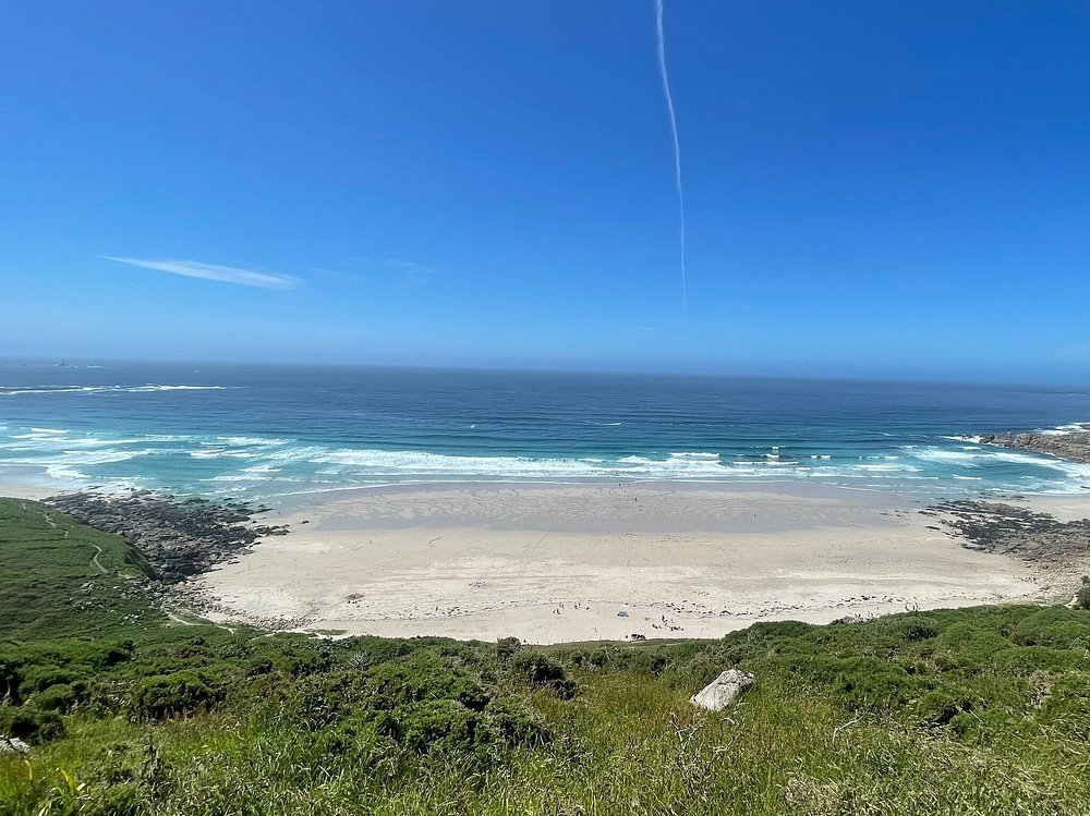 Wide sandy bay at Gwenver Beach in Cornwall, with rolling waves and rugged coastline