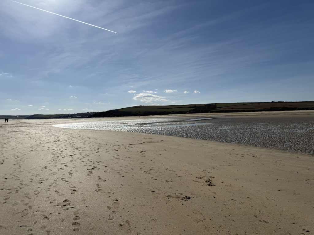 Rock Beach in Cornwall at low tide with wide sandy shoreline, shallow water and open estuary views