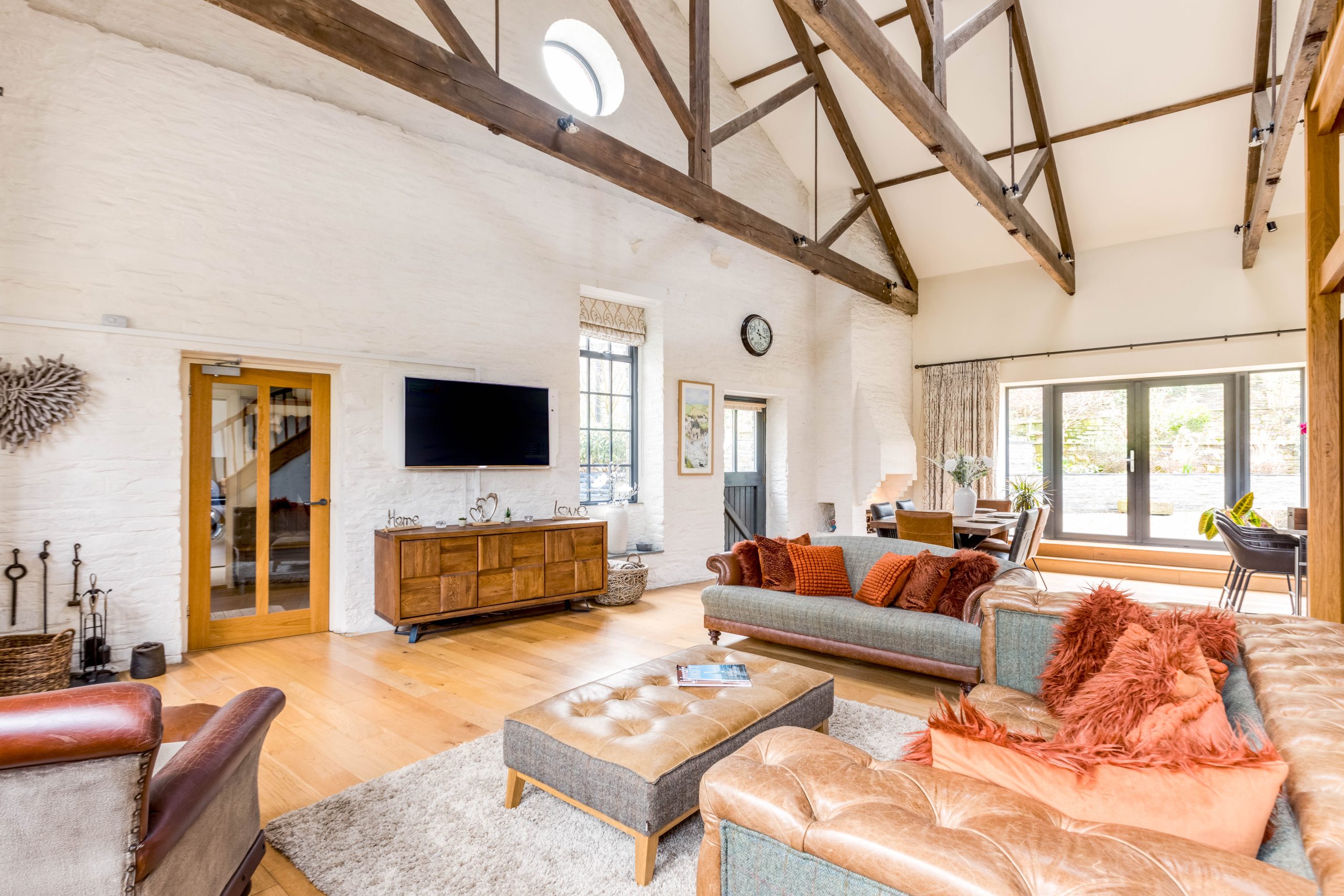 Open-plan living area at The Forge holiday home in Cornwall with exposed beams and garden doors
