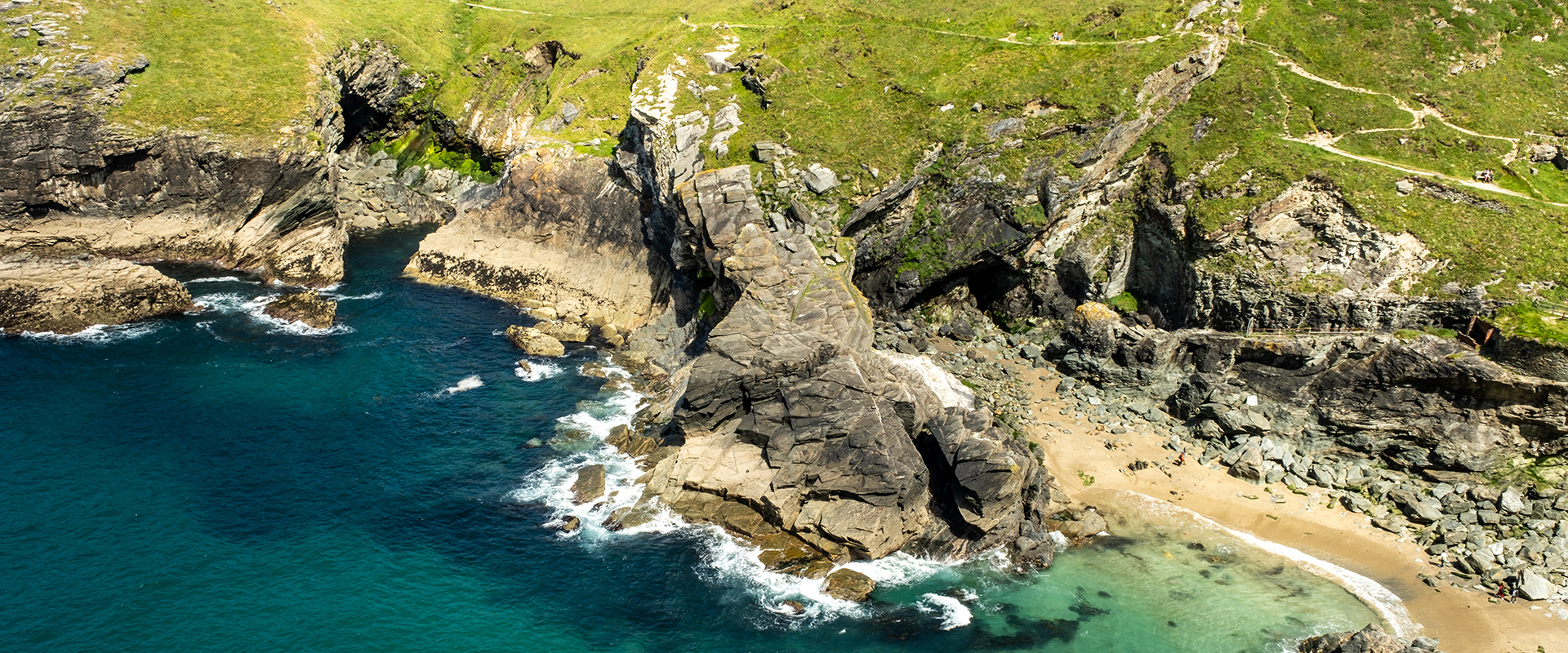 Aerial view of Tintagel Haven (Castle Cove) with turquoise sea and rugged cliffs in North Cornwall