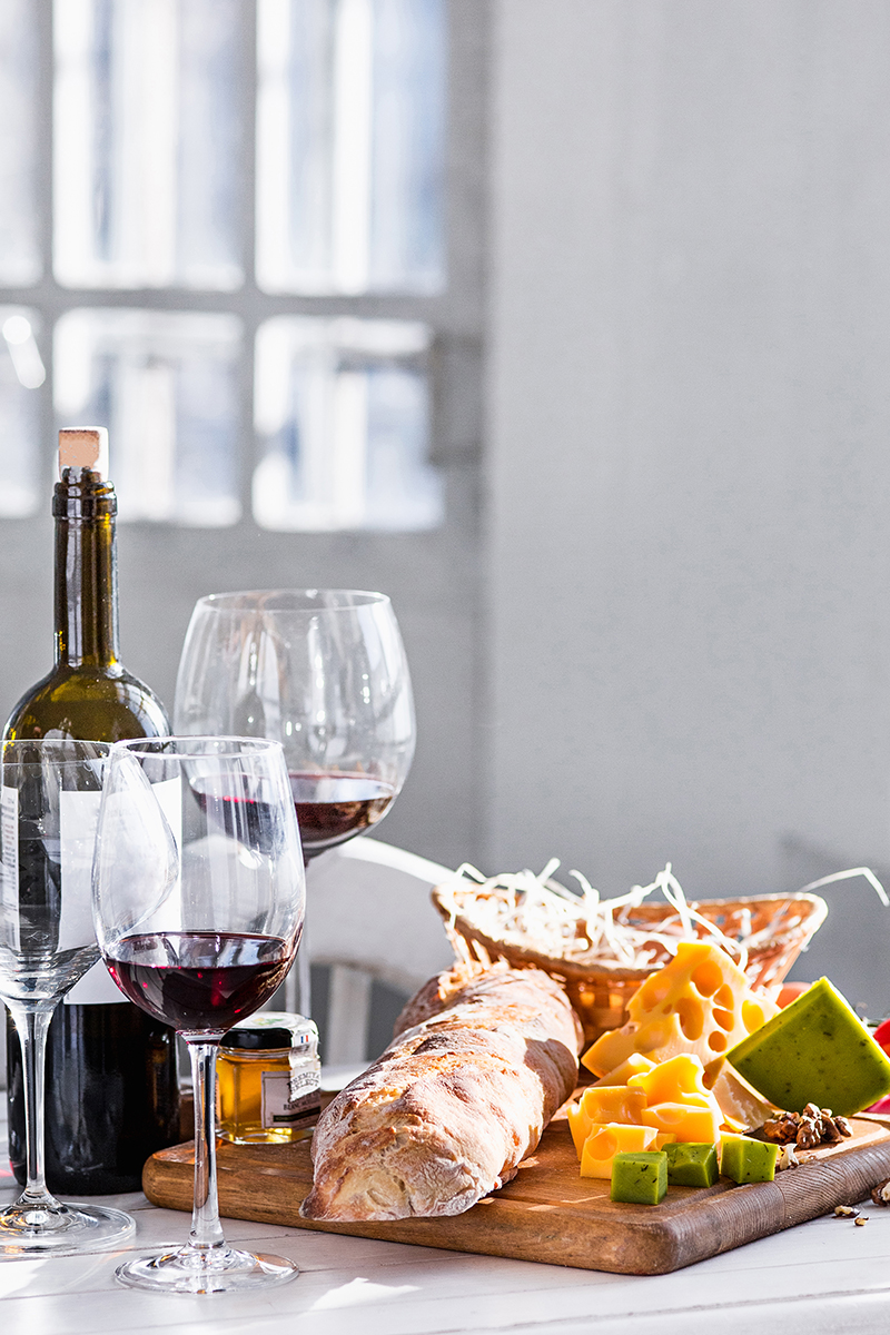 Wine, fresh baguette and artisan cheese arranged on a wooden board in a holiday cottage dining space
