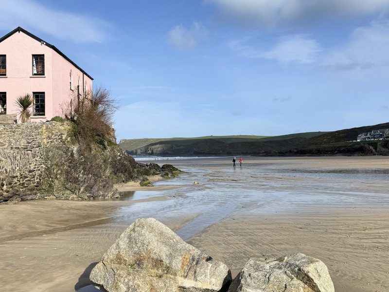 Polzeath Beach at low tide with sandy shoreline and coastal cottages